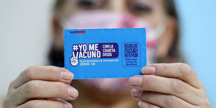 A person shows a vaccination card for the coronavirus disease COVID-19 at a vaccination centre in Santiago, on 10 January 2022. - Chile started administering today a fourth COVID-19 vaccine dose to people over the age of 12 with weakened immune systems. (Photo by Javier TORRES / AFP)