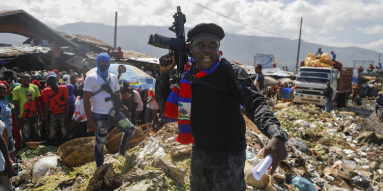 FILE - Barbecue, the leader of the "G9 and Family" gang, stands next to garbage to call attention to the conditions people live in as he leads a march against kidnapping through La Saline neighborhood in Port-au-Prince, Haiti, Friday, Oct. 22, 2021. The group said they were also protesting poverty and for justice in the slaying of President Jovenel Moise. (AP Photo/Odelyn Joseph, File)
